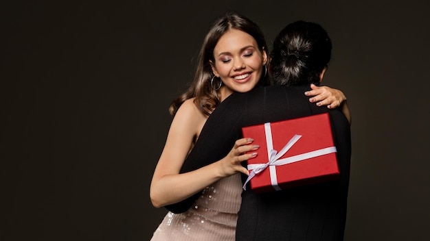 Happy pretty young lady with xmas present hugging boyfriend