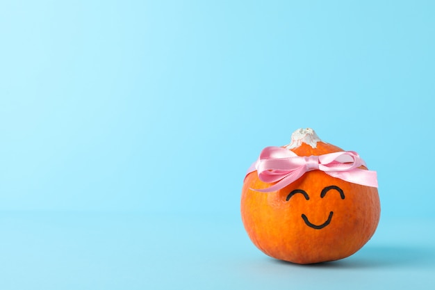 Happy pumpkin with bow on blue, space for text