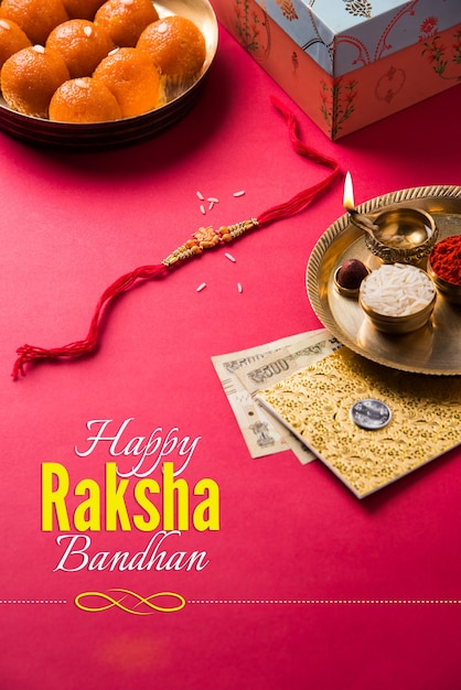 Happy Raksha Bandhan or Rakhi Greeting Card using Designer thread, Diya, Pooja Thali, Gift box, Indian Paper Currency notes and sweets etc. Moody lighting, selective focus