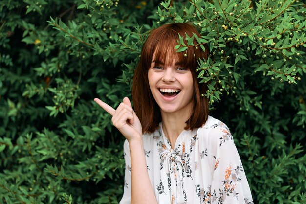 Photo happy redhead woman smiling and pointing finger in front of her