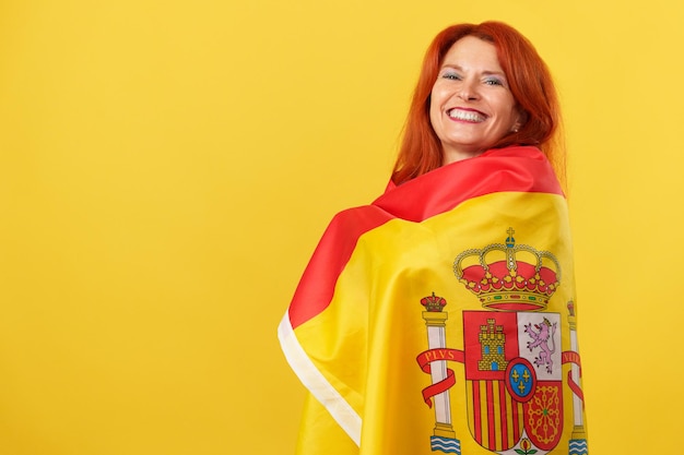 Happy redheaded mature woman wrapping with a spanish national flag