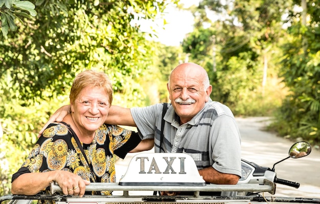 Happy retired senior couple taking travel photo at scooter taxi tour