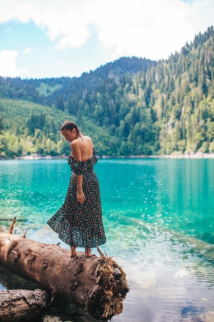 Happy romantic woman sitting by lake splashing water