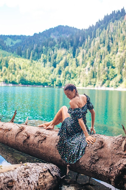 Happy romantic woman sitting by lake splashing water