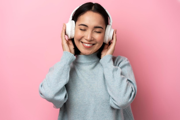 Happy satisfied girl standing listening favourite music with headphones