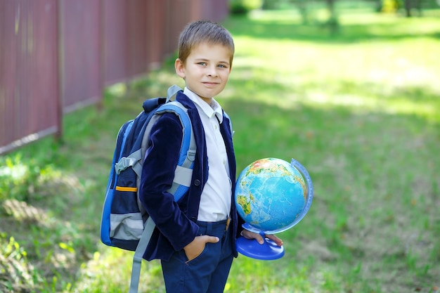 happy schoolboy with globe first time to school