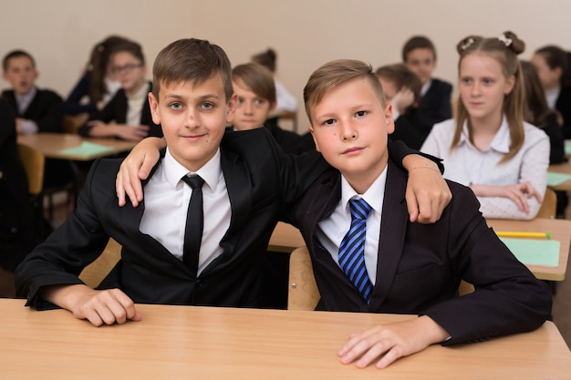 Happy schoolchildren sit at a desk in the classroom