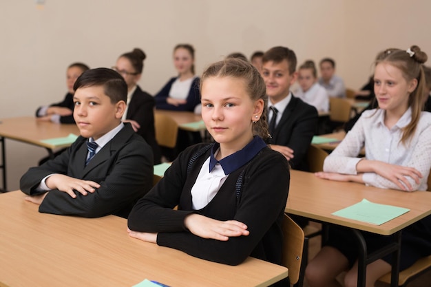 Happy schoolchildren sit at a desk in the classroom