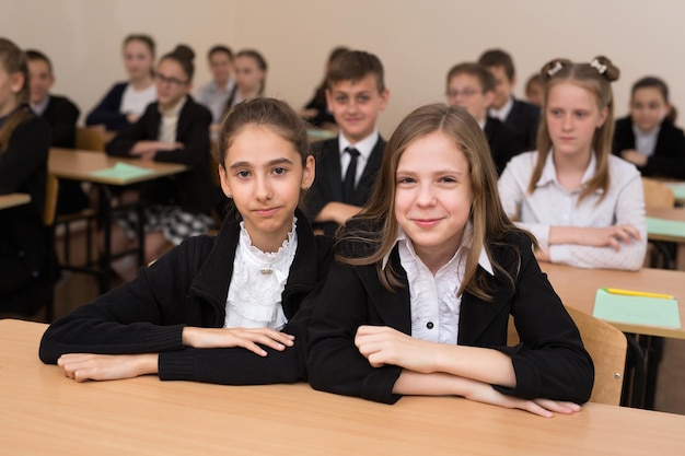 Happy schoolchildren sit at a desk in the classroom