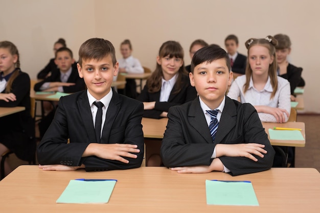 Happy schoolchildren sit at a desk in the classroom