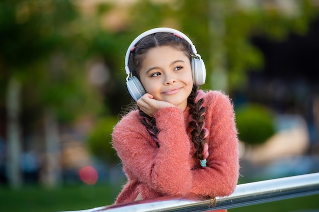 Happy schoolgirl wearing headphones for school Teenage girl listening to headphones