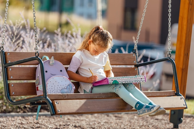 Happy schoolgirl with a backpack smiling and reading notes in notebooks