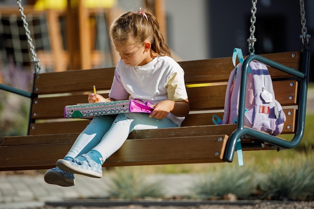 Happy schoolgirl with a backpack smiling and reading notes in notebooks