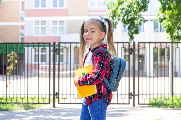 Happy schoolgirl with a textbook in her hands in a white Tshirt and a plaid shirt