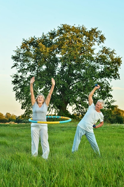 Happy senior couple doing exercises in autumnal park