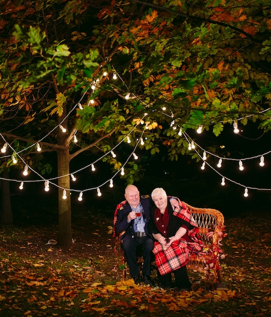 Happy senior couple drinking tea in the evening sitting on the couch.