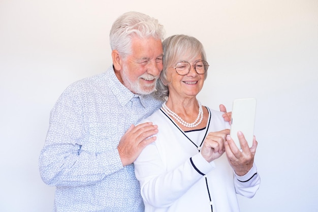 Happy senior couple holding smartphone looking at cellphone screen laughing relaxing together