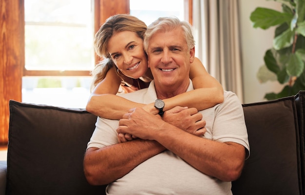 Happy senior couple hug and relax for love care and bonding time with smile at home on living room sofa Portrait of elderly man and woman in relationship happiness hugging and relaxing on couch