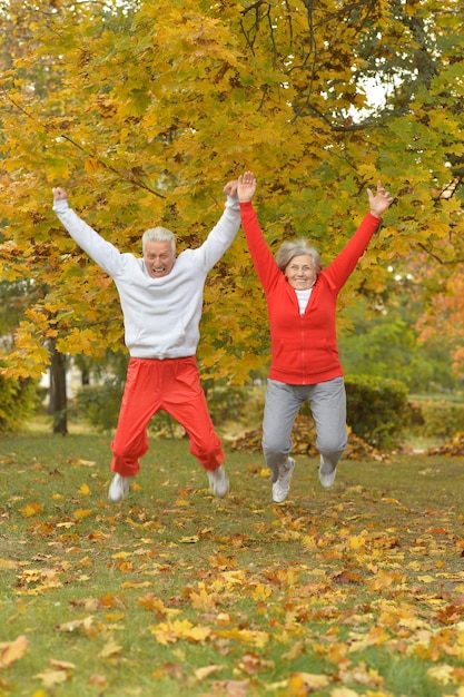 Happy senior couple jumping  in autumn park