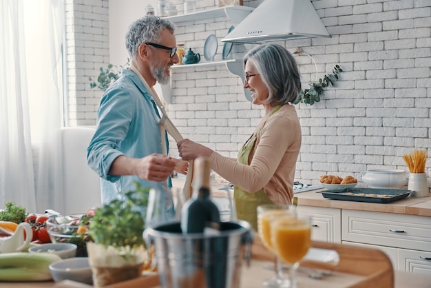 Happy senior couple preparing to cook a dinner and smiling while spending time at home