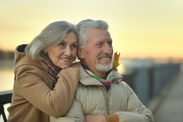 Happy senior couple relax in autumn park near river