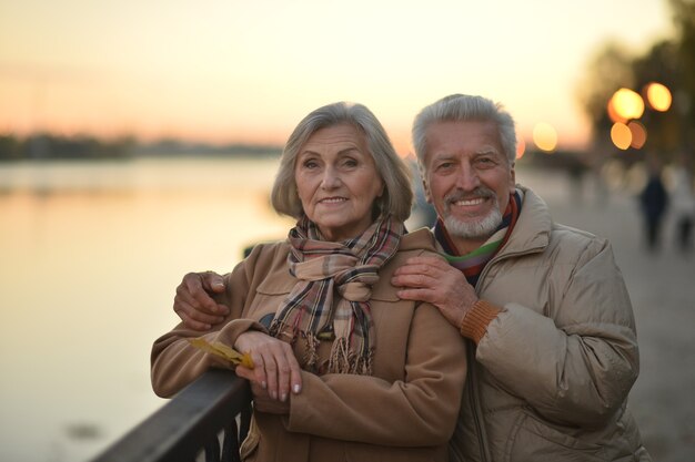 Happy senior couple relax in autumn park near river