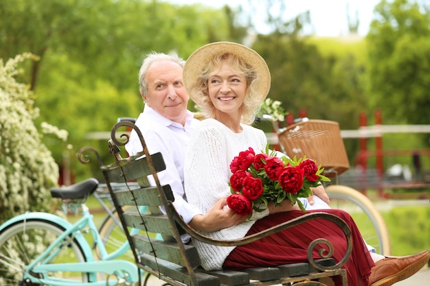 Happy senior couple sitting on bench in park