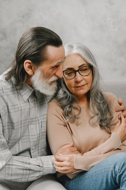 Happy senior couple sitting on couch at home and talking. Quality time concept.