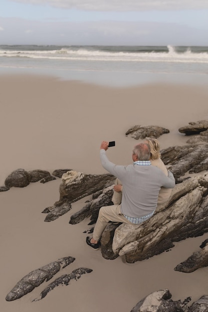 Photo happy senior couple taking selfie with mobile phone at the beach