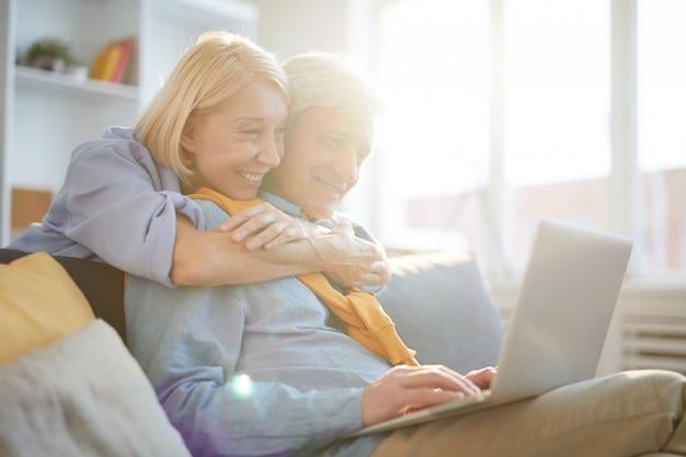 Happy Senior Couple Using Laptop in Sunlight