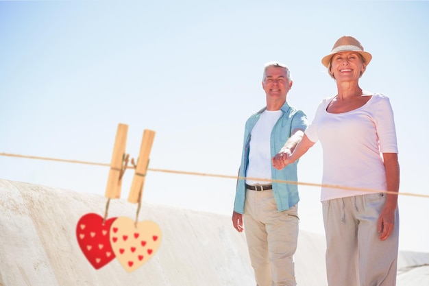 Happy senior couple walking on the pier against hearts hanging on the line