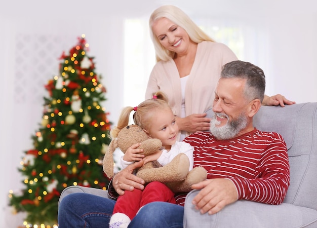 Happy senior couple with granddaughter celebrating Christmas at home