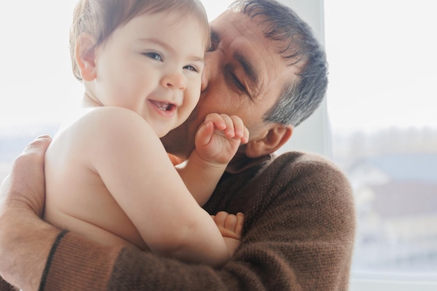 Happy senior grandpa and cute kid granddaughter playing having fun game at home