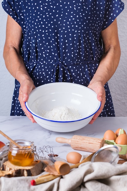 Happy senior mature woman, grandmother cooking, kneading dough, baking pie, cake,  cookies. Autumn activity at home, in a cozy kitchen.