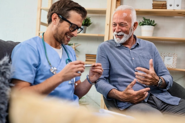 Happy senior patient communicating with healthcare worker who is being in a home visit