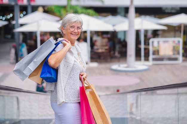 Happy senior woman carrying shopping bags enjoying shopping consumerism sales customer shopping concept