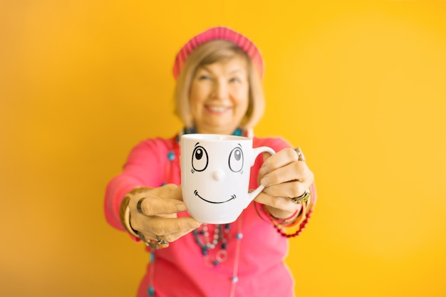 Happy Senior woman funny face drinking a cup of coffee or tea in stylish clothes