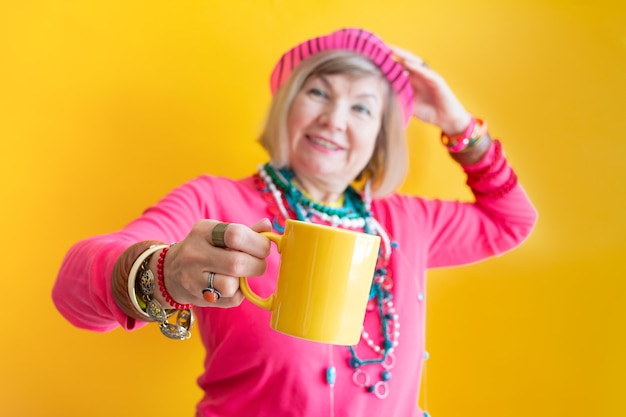 Happy Senior woman funny face drinking a cup of coffee or tea in stylish clothes