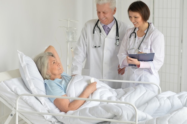 Happy Senior woman in hospital with caring doctors