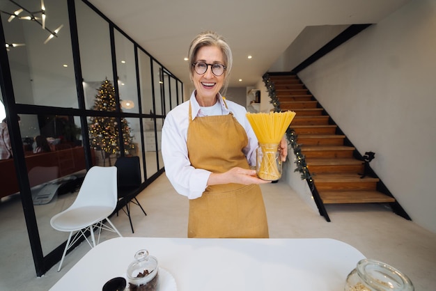 Happy senior woman showing pasta on camera