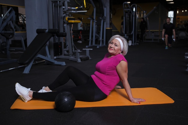 Happy senior woman smiling to the camera resting after gym workout