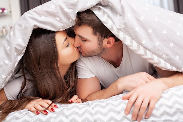 Happy sensual young couple lying in bed together