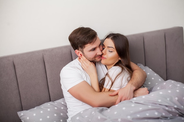 Happy sensual young couple lying in bed together