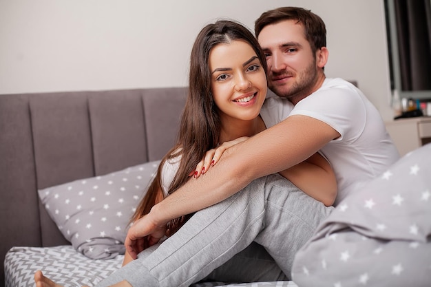 Happy sensual young couple lying in bed together