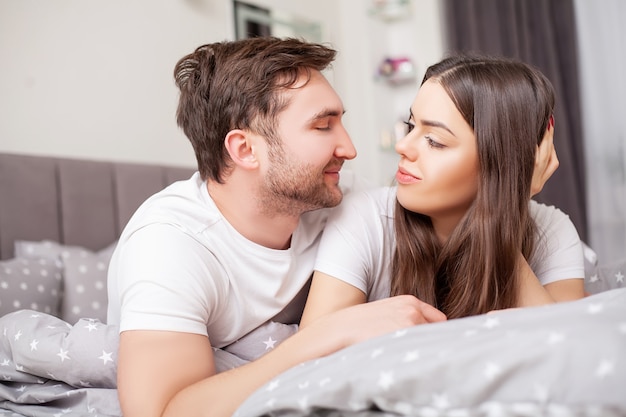 Happy sensual young couple lying in bed together