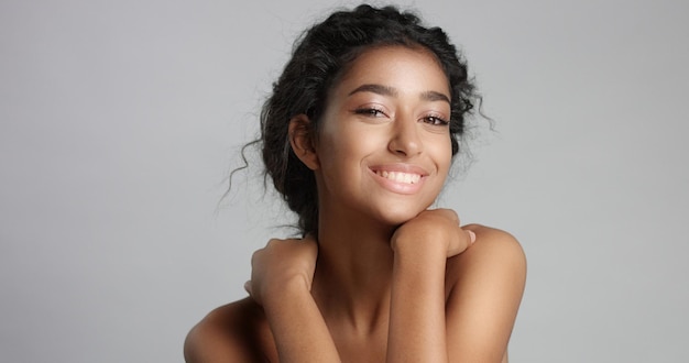 Happy serene young woman with beautiful olive skin and curly hair ideal skin and brown eyes in studio