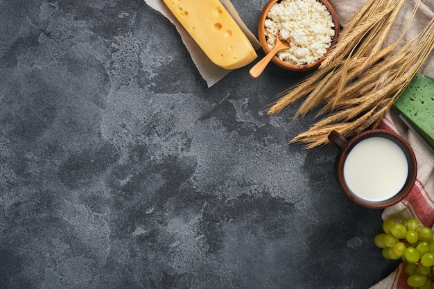 Happy Shavuot Background for Shavuot traditional religious Jewish celebration Milk and cheese ripe wheat and fruits Dairy products over old dark grey background Shavuot concept Top view Mock up