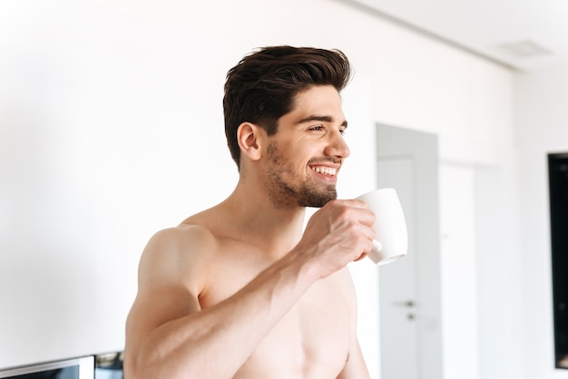 Happy shirtless man drinking coffee