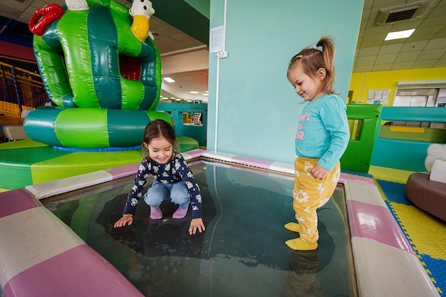 Happy sisters playing at indoor play center playground in water trampoline