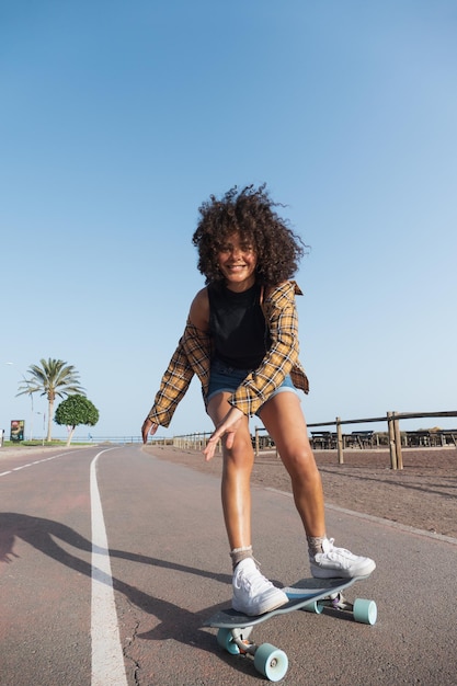 Happy skater young woman with afro hair skating on the street